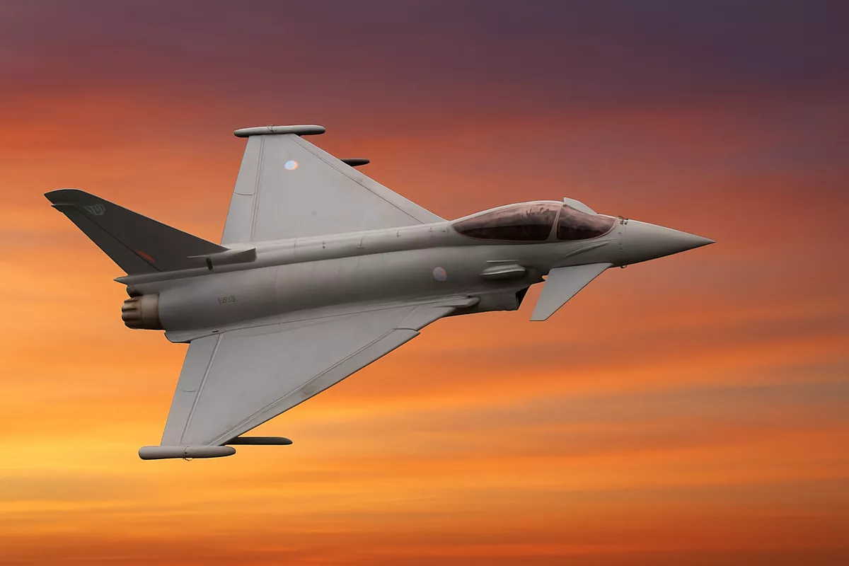 Myśliwiec leci, przecinając niebo o zachodzie słońca. Tło jest dynamiczne, z ciepłymi, pomarańczowo-fioletowymi odcieniami chmur, podkreślającymi sylwetkę samolotu.