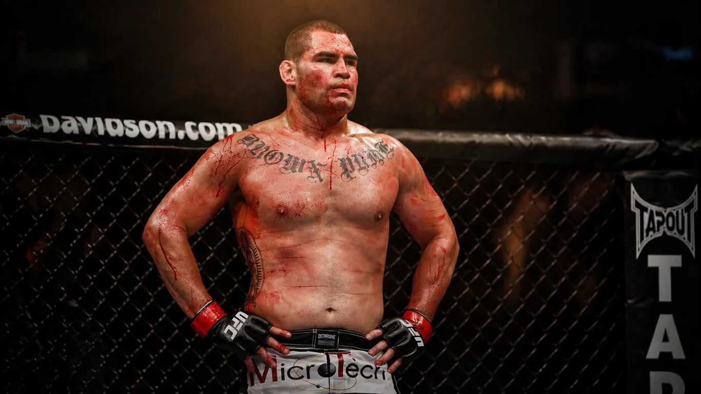 Cain Velasquez w klatce UFC po walce, z widoczną sylwetką i ikonicznym tatuażem na klatce piersiowej.