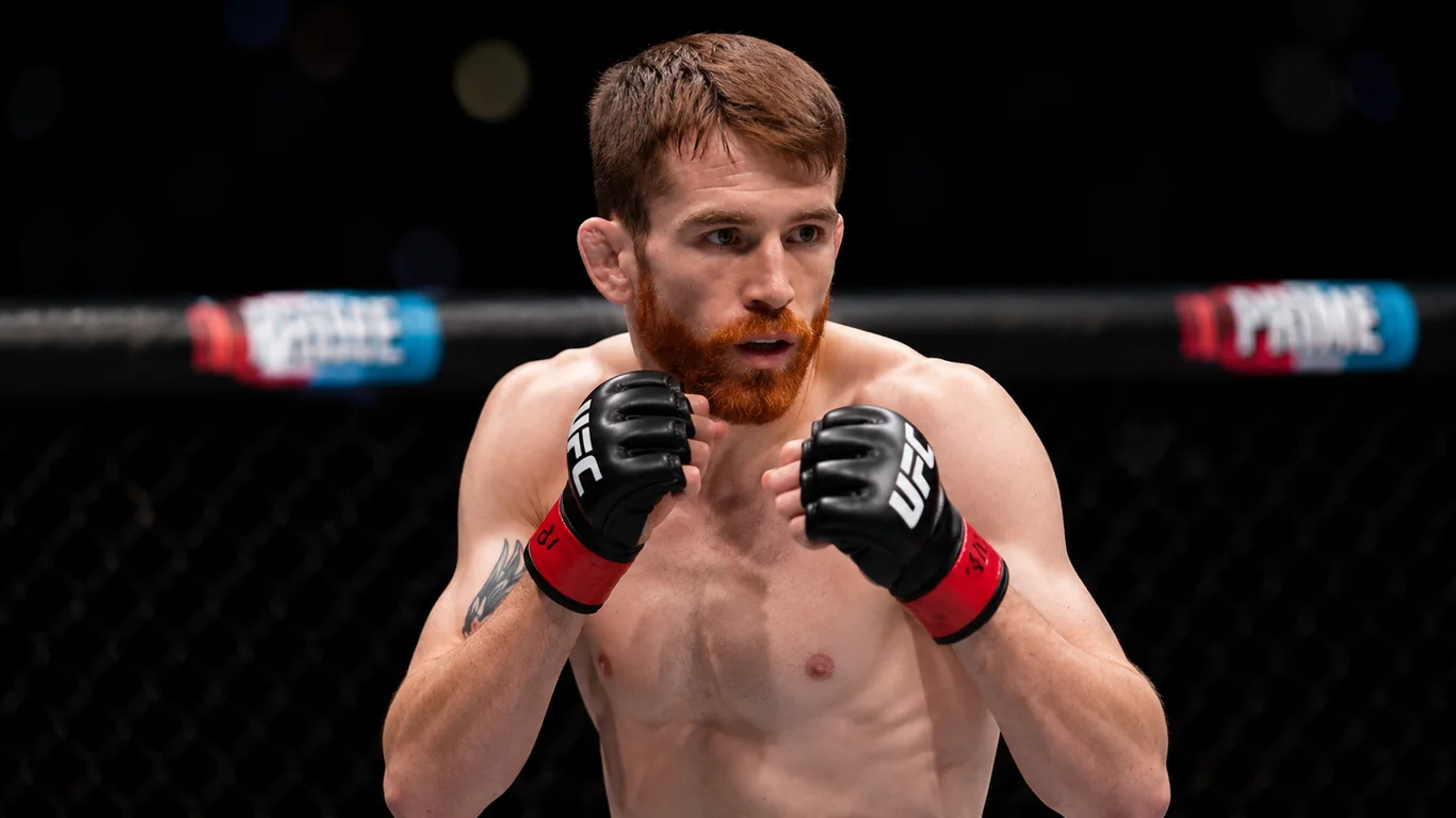 Cory Sandhagen w oktagonie UFC w pozycji strikerskiej, ręce uniesione w gardzie, dynamiczna walka.
