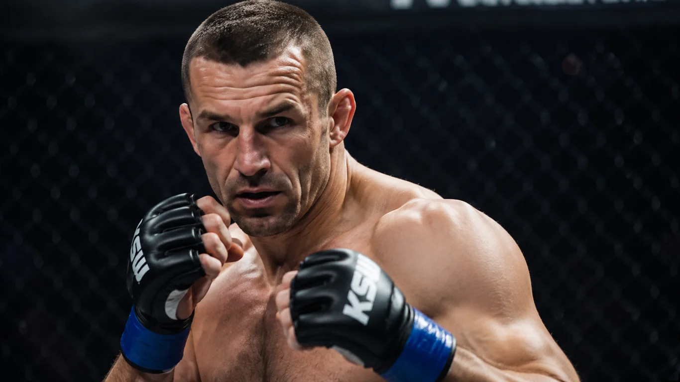 Tomasz „Gorilla" Drwal w klatce MMA, muskularna sylwetka polskiego zawodnika wagi średniej z intensywnym spojrzeniem przed walką.