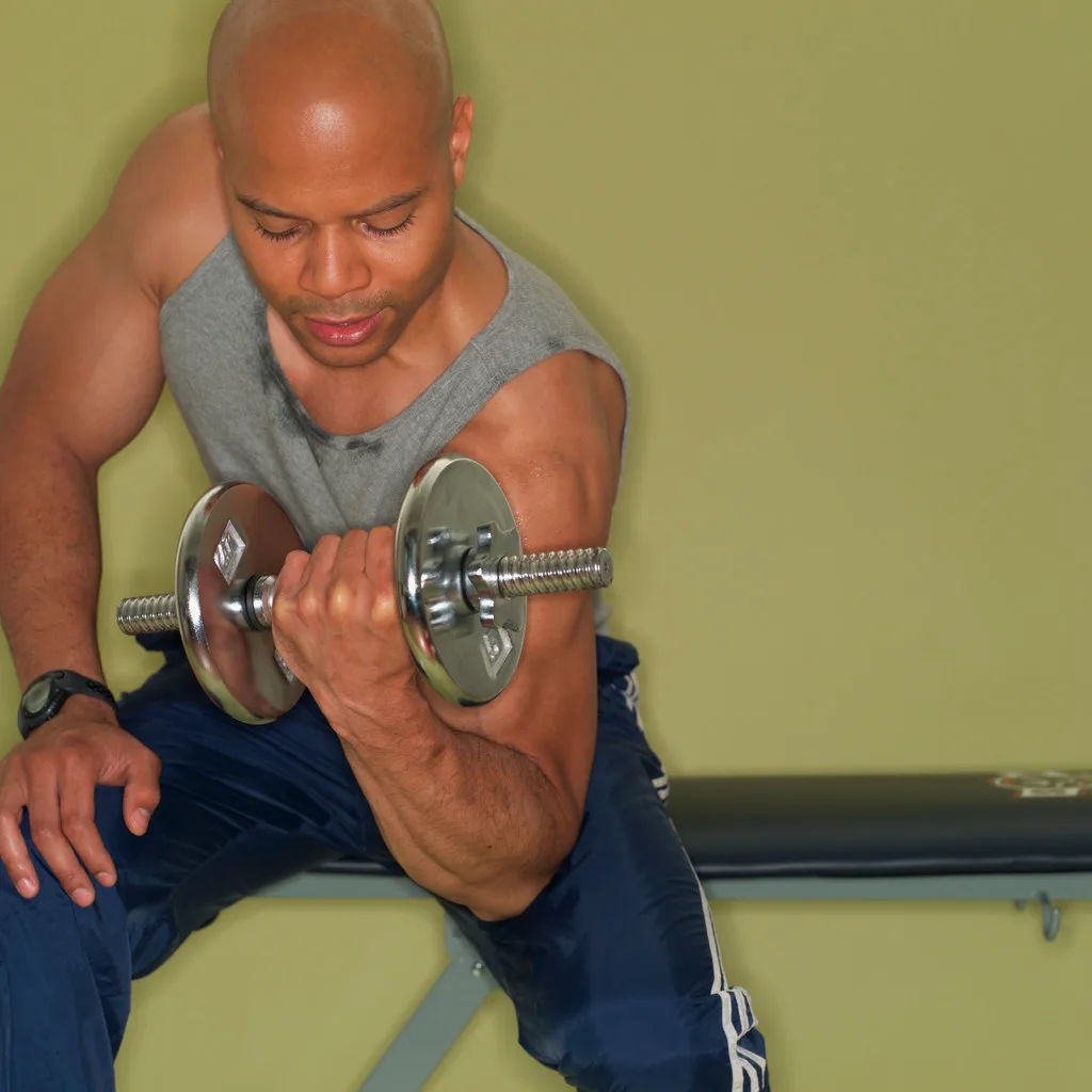 Mężczyzna wykonuje uginanie ramion z hantlą, koncentrując pracę na bicepsie