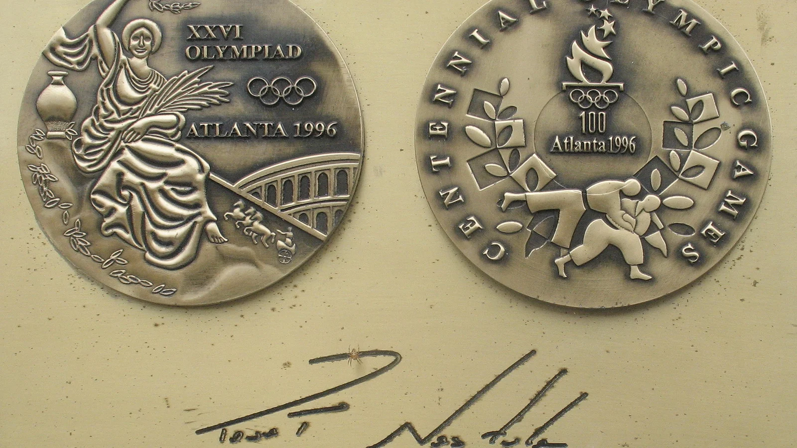 Replika złotego medalu olimpijskiego z Atlanty 1996 z obu stron i podpis Pawła Nastuli na tablicy w Alei Gwiazd Sportu w Dziwnowie