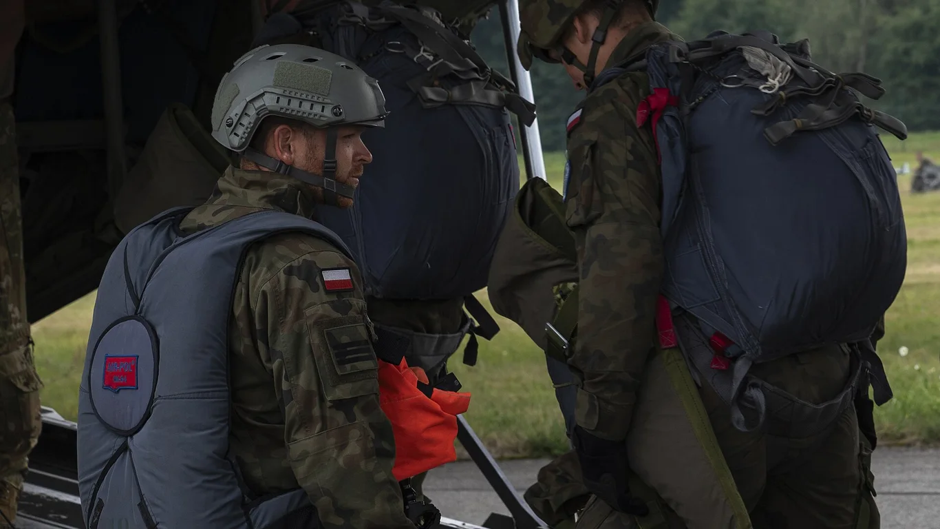 Żołnierze 18 Batalionu Powietrznodesantowego w hełmach, ze spadochronami na plecach, wchodzą na pokład samolotu C-130J